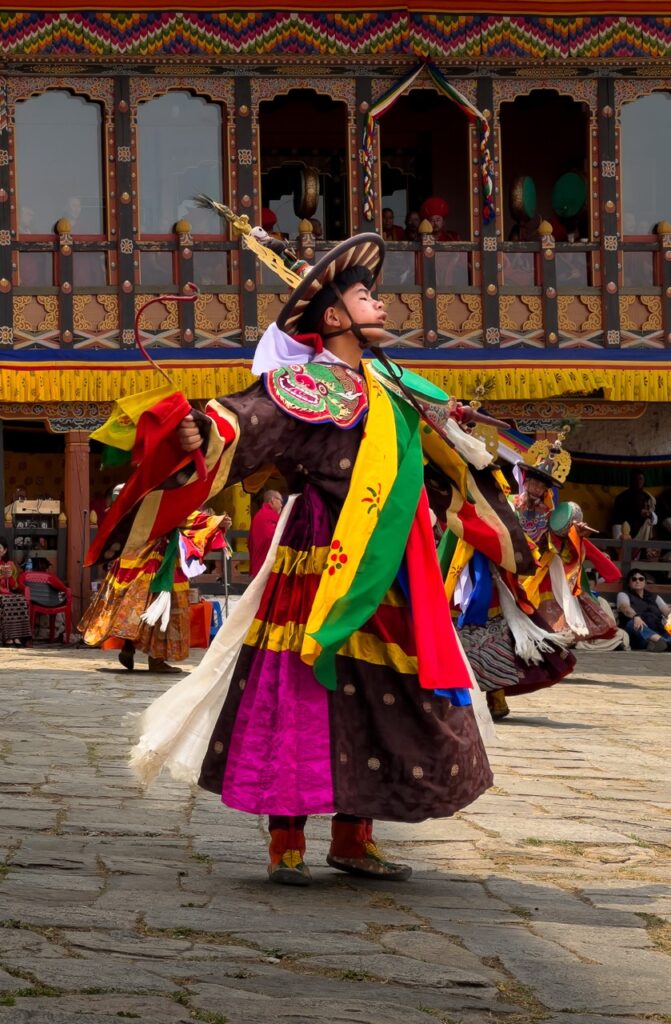 Danzante en el patio exterior del Dzong de Paro durante la celebracion del Tsechu, con su traje tradicional de seda y sombrero negro, en Bután (Bhutan)