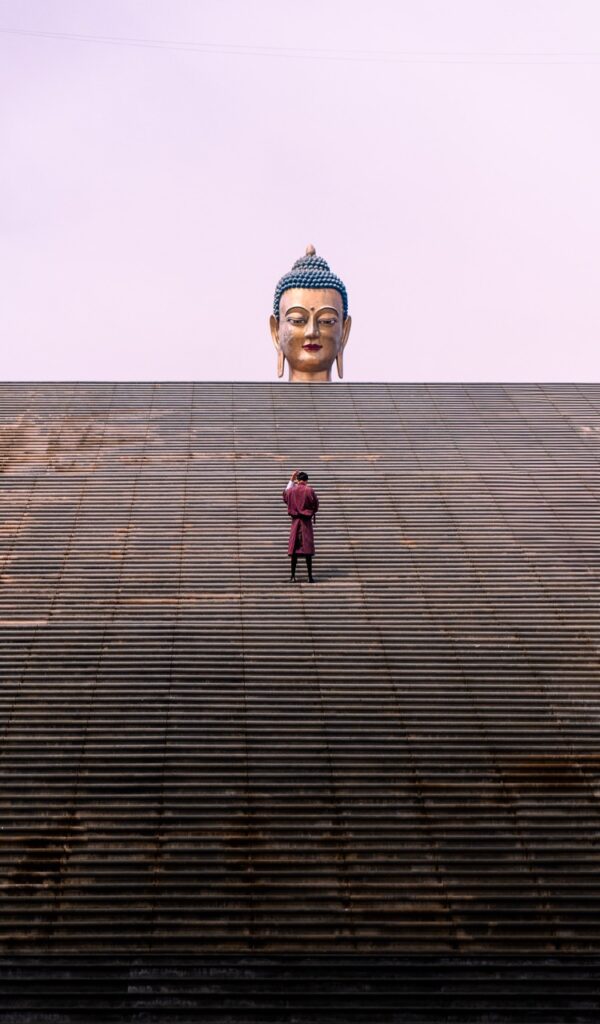 Local subiendo escaleras con su traje tradicional Gho hacia el Gran Buda en Timbu, Bután (Bhutan)