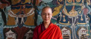 Monja budista apoyada en un colorido mural del convento Sangchhen Dorji Lhuendrup Nunnery en Punakha
