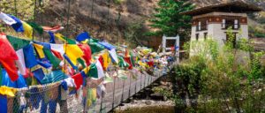 Puente colgante lleno de banderas de oración budistas de colores en Bután (Bhutan)