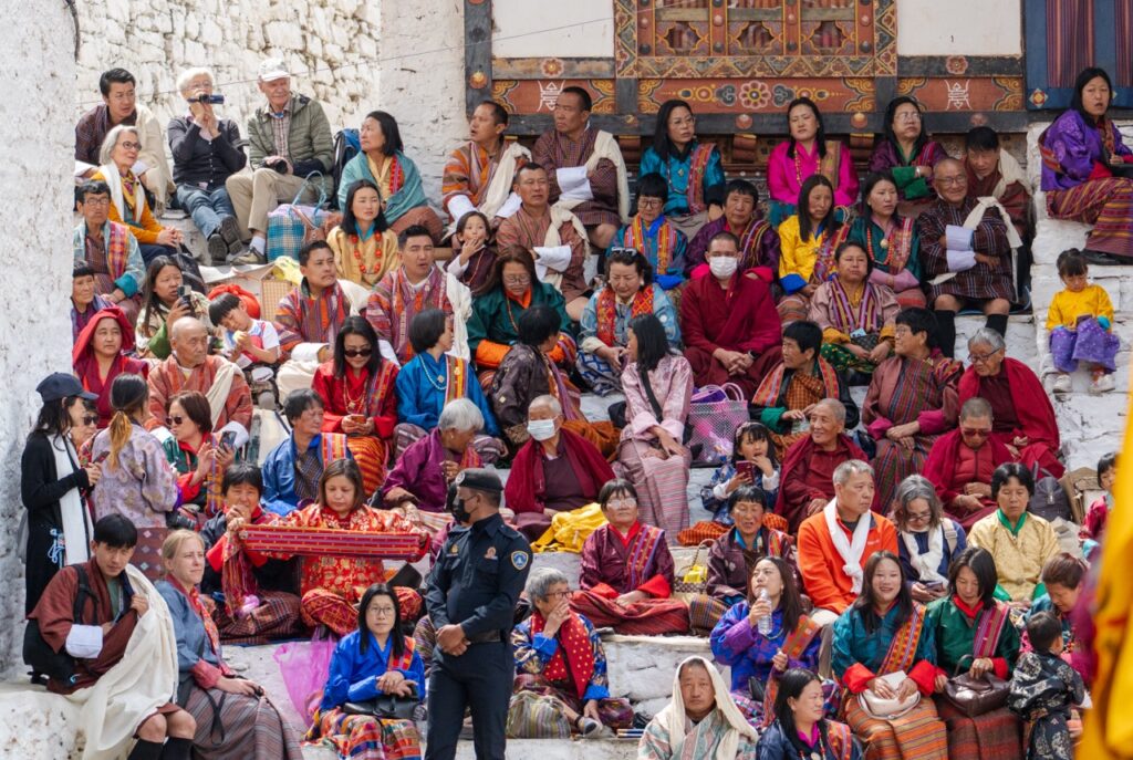 Familias y visitantes en el patio del Dzong de Paro para presenciar los bailes del Tsechu
